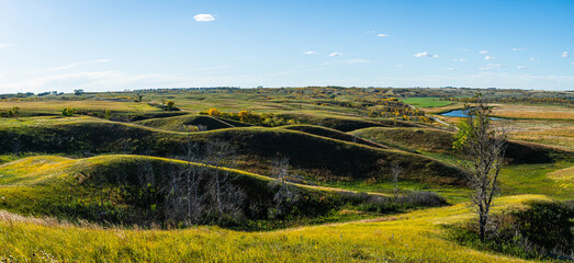 panorama of the rolling hills across the landscape of north dakota in late afternoon sun.