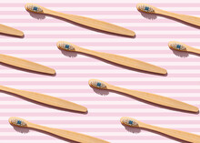 Pattern Of Wooden Toothbrushes Flat Laid Against Pink Striped Background
