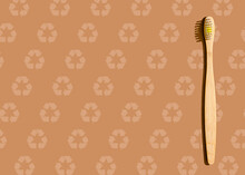 Studio Shot Of Wooden Toothbrush Lying Against Brown Pattern With Recycling Symbols