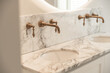 © ADDICTIVE STOCK - Bathroom with marble sinks with bronze taps and illuminated mirror