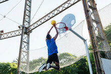 Young Man Dunking Basketball While Playing At Sports Court
