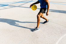 Young Man Dribbling Basketball At Sports Court During Sunny Day