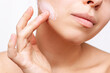 © Марина Демешко - Cropped shot of a young caucasian woman touching the face with her hand applying a cream on the skin isolated on a white background. Nourishing moisturizing cream. Cosmetology and beauty concept