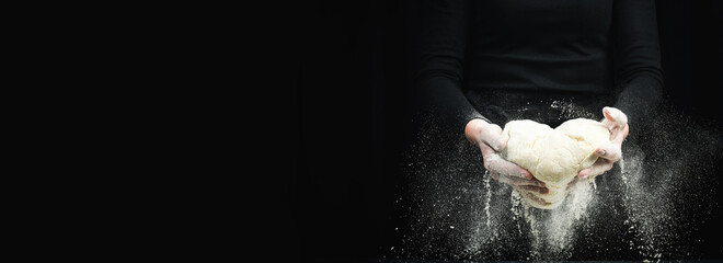 Wall Mural - Cooking dough by chef hands for homemade pastry bread with flour splash. On a dark background.