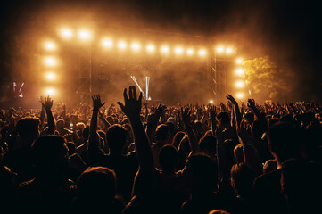 Silhouettes of concert crowd in front of bright stage lights on a music festival