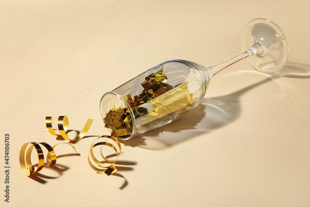 Composition with champagne glass, confetti and serpentine on color background