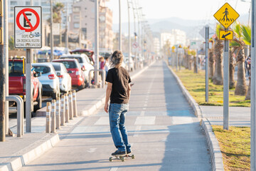 Wall Mural - latin mature or senior man skateboard on bikeway in La Serena at sunset	