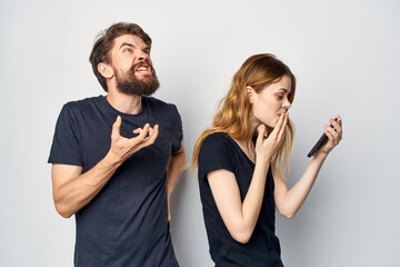 Wall Mural - cheerful young couple in black t-shirts phone fun together friendship light background