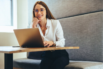 Wall Mural - Professional woman smiling at the camera in a modern workspace