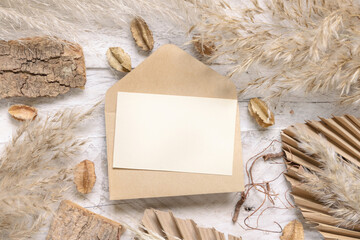 Wall Mural - Blank card and envelope on white wooden table near dried plants top view