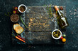 Leinwandbild Motiv Wooden board on a black stone table with vegetables and spices. Food background. Top view. Rustic style.