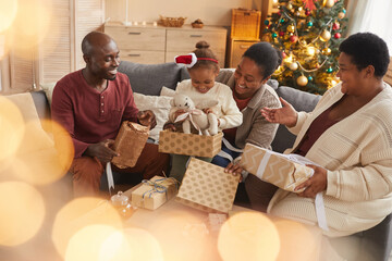 Wall Mural - Magical portrait of happy African-American family opening Christmas gifts while enjoying holiday season at home