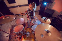 Above View Portrait Of Young Woman Playing Drums In Recording Studio Lit By Red Lights, Copy Space