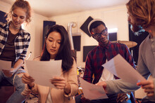 Portrait Of Multi-ethnic Band Writing Music Together, All Holding Lyric Sheets While Working In Recording Studio