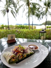 Wall Mural - dinner plate at a luxury restaurant by the ocean with meat and salad. Thai spring rolls