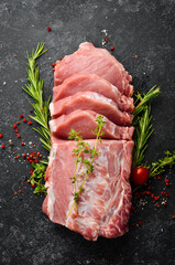 Wall Mural - Raw pork fillet with spices on a black stone background. Meat. Top view. Rustic style.
