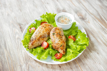 food,fried chicken breasts on green lettuce leaves,fresh cherry tomatoes and creamy spicy sauce,keto diet recipe,selective focus