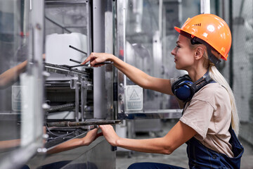 confident woman in work clothes at factory repairing robotic machine with wrench tool, caucasian young lady in protective workwear uniform mastered the male profession. feminism concept