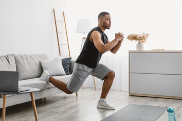 Sporty Black Guy Doing Single-Leg Squats Exercising Online At Home