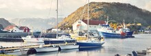 Motorboats, Sailing And Fishing Boats Moored To A Pier In A Small Village In Fjords. Hidra Island, Rogaland Region, Norway. Traditional Architecture. Dramatic Evening Sky. Travel Destinations Theme