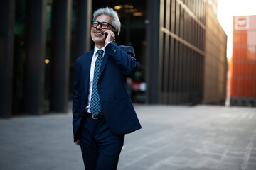 Wall Mural - Senior businessman outdoors. Middle-aged businessman talking to the phone