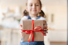Small Cute Daughter Girl Holding Focused Present Gift Box With Red Ribbon, Giving Receiving Presents On Holiday Event, Celebration Christmas Birthday Mother`s Day At Home