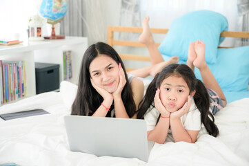 child girl person 2 sisters watching media and learning on laptop, online communication at home