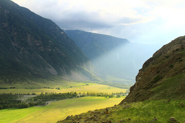 Wall Mural - The Chulyshman river in a green valley in the Ak-Kurum tract, a wide river valley with glades and trees, rocky slopes of huge mountains, a sunbeam shines into the valley, Altai, summer