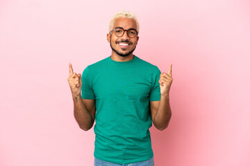 Wall Mural - Young Colombian handsome man isolated on pink background pointing up a great idea