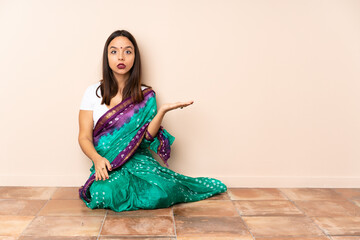 Young Indian woman sitting on the floor making doubts gesture