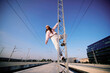 © chika_milan - Rebellious teenage girl climbing on the metal construction at the train station.
