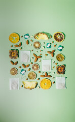 Dried fruit in a conceptual way. Oranges, lemons and limes. Tea bags and almonds. Green background.