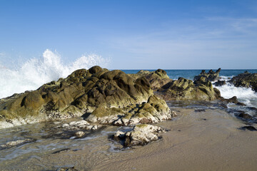 Wall Mural - Ocean water splashing against rocks along the shore