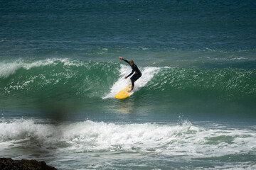 Wall Mural - male surfer catching waves surfing at south coast beach on a bright warm sunny day on clear blue water