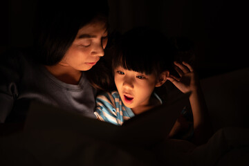 Wall Mural - young Asian mother and little daughter girl on bed, cozy love sleepy at childhood home, at night