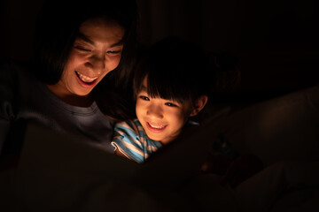 Wall Mural - young Asian mother and little daughter girl on bed, cozy love sleepy at childhood home, at night