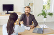 Happy handsome bearded man in suit sitting at office table, smiling and shaking hands with insurance company worker, loan broker, or client manager after making successful deal and signing contract