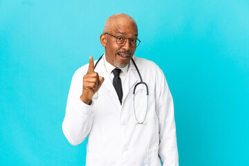 Wall Mural - Senior doctor man isolated on blue background intending to realizes the solution while lifting a finger up