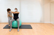 © Jordi Mora - Physiotherapist helping a pregnant woman to exercise sitting on a fitness ball