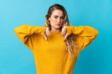 Young Brazilian Woman Isolated On Blue Background Showing Thumb Down With Two Hands