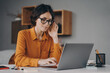 © VK Studio - ocused Spanish woman in glasses sits at desk and typing on laptop during remote work at home