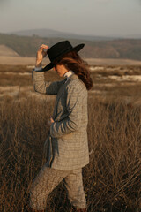 Wall Mural - beautiful woman with dark hair in elegant clothes posing in the field