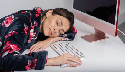 Wiltshire, UK. 2021. Woman working from home asleep by her desktop computer and keyboard.