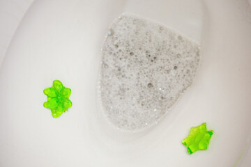 Two green gel flowers on the side of a toilet bowl.