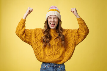 Relieved attractive fashionable university female student yelling proudly raise clenched fists victory cheer gesture celebrating win successful achievement accomplishment goal, yellow background