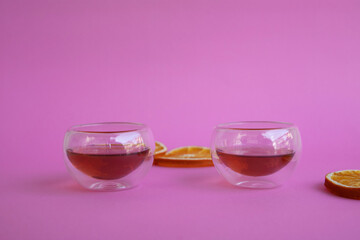 2 cups of Chinese tea on coloured background and slices of orange