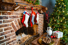 Socks For A Gift From Santa Claus Hang On The Fireplace. A Large Christmas Tree