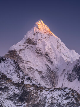 Triangle snow peak in last sun light under dark blue sky in Nepal