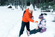 Family on a winter walk in the winter forest. Young woman and girl 5 years old drink hot tea and eat.