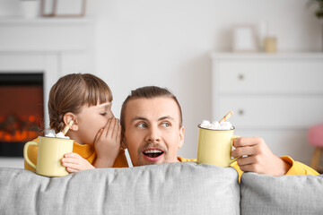 Sticker - Happy daughter and father with cups of hot cocoa behind sofa at home